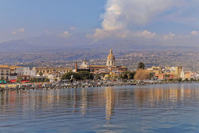 Coast of riposto with a view of the city center and mount etna in the background