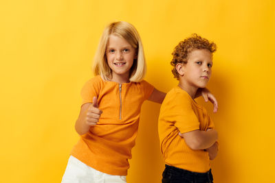 Portrait of sibling against yellow background