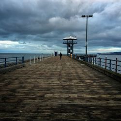 Pier on sea against cloudy sky