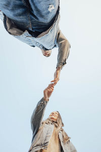 Hands of man and woman on blue sky background