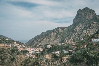 Scenic view of town by mountains against sky