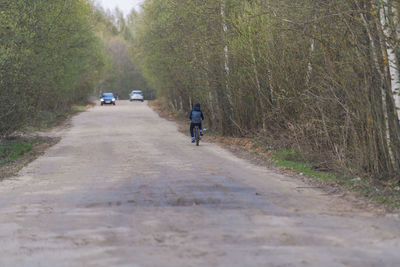 Rear view of man riding motorcycle on road