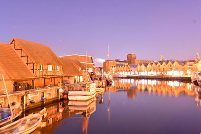 Panoramic view of illuminated buildings by river against sky at night