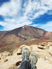 Low section of person on mountain against sky
