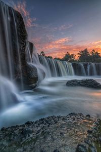 Scenic view of waterfall against sky during sunset