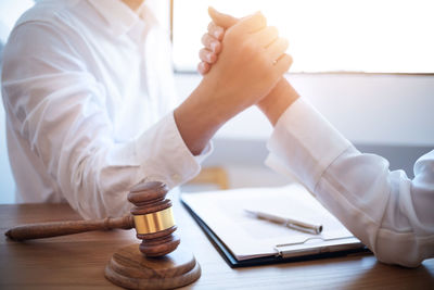 Midsection of man holding glass while sitting on table