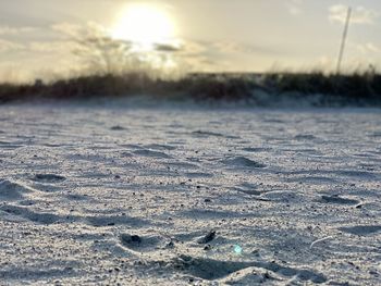 Surface level of frozen land against sky during sunset