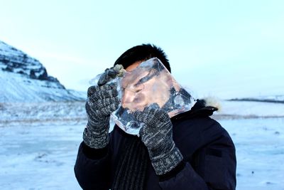 Close-up of man holding ice against sky