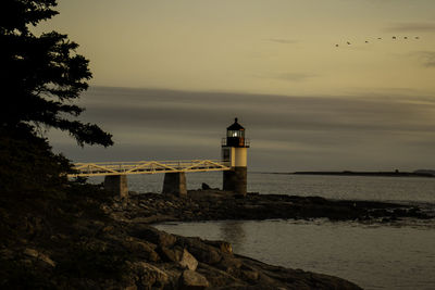 Lighthouse by sea against sky during sunset at marshall point