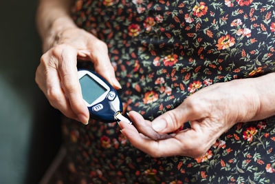 Midsection of woman testing blood sugar