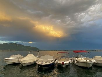 Boats moored in sea against sky during sunset