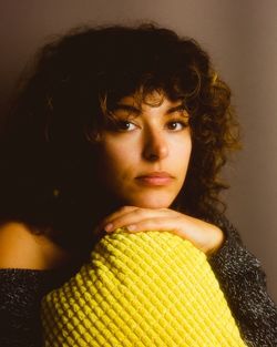 Portrait of young woman against brown background