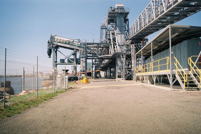 Road by factory against sky