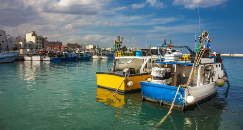 Fishing boats moored in sea against sky