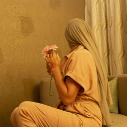 Side view of woman holding yellow flower