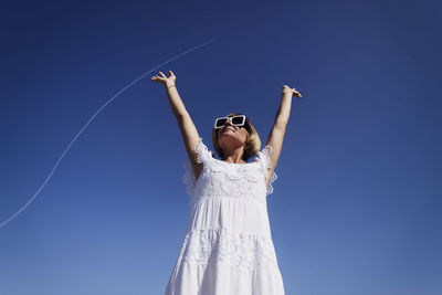 A happy, confident woman rejoices by raising her hands up to the flying plane. positive, motivation