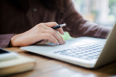 Midsection of woman using mobile phone on table