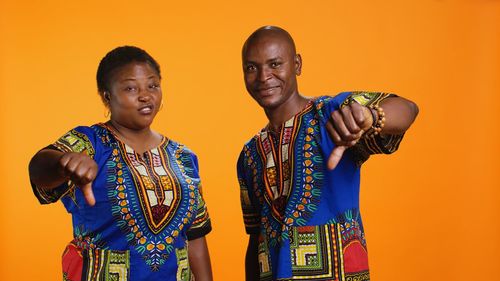 Portrait of happy friends standing against yellow background