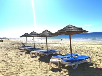 Deck chairs on beach against blue sky