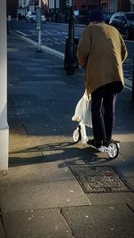 Low section of man with umbrella on street