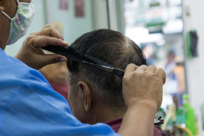 Barber cutting man hair in salon