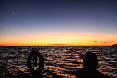Rear view of woman on boat against sea during sunset