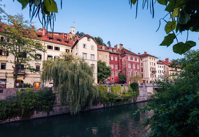 Houses by river and buildings against sky