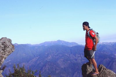 Full length of hiker standing on mountain against sky
