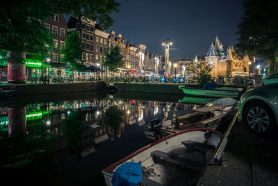 Boats moored on canal against illuminated historic building in city at night