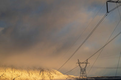 Low angle view of electricity pylon on field against sky