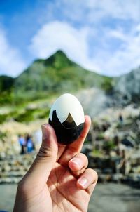 Close-up of hand holding ice cream against mountain