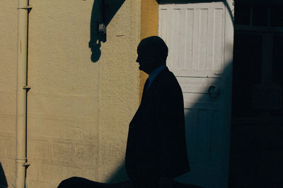 Side view of silhouette man standing against building in city