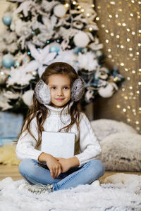 Portrait of cute girl sitting on snow