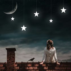 Woman looking at artificial stars hanging against sky