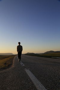 Rear view of man on road against clear sky