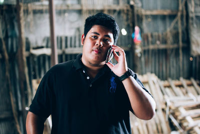 Young man holding camera while standing outdoors