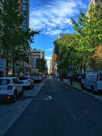 Cars on street in city against sky