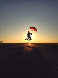 Silhouette person jumping on beach against clear sky