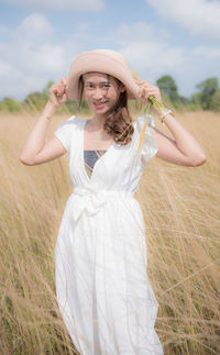 Portrait of woman in hat standing on field