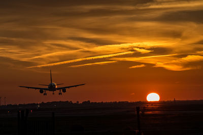 Airplane taking off against sky during sunset