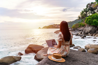 Rear view of woman sitting on beach