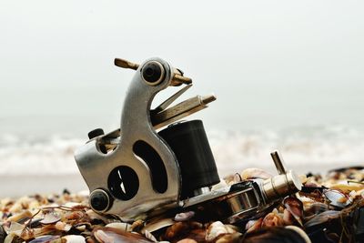 Close-up of machine on beach against sky