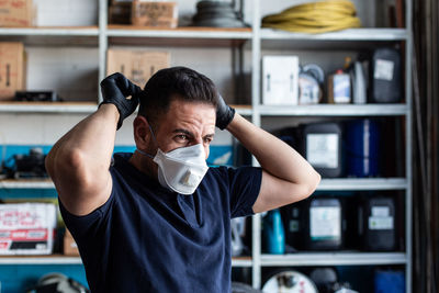 Male employee putting white face mask for work in garage