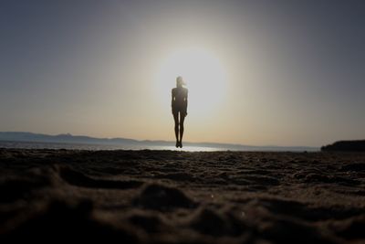 Rear view of silhouette man standing on beach during sunset