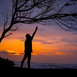 Silhouette man standing on beach against sky during sunset