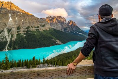 Rear view of man standing by railing against mountains