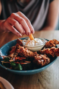 Midsection of person preparing food in bowl on table