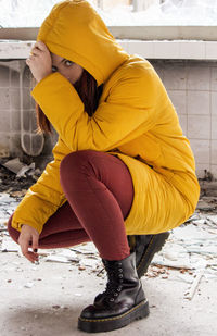 Young woman in yellow hood jacket knelt down