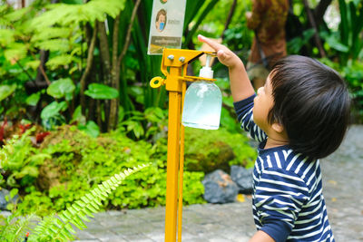 Side view of boy holding plant