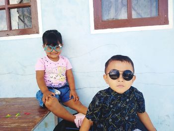 Cute siblings wearing eyewear against house